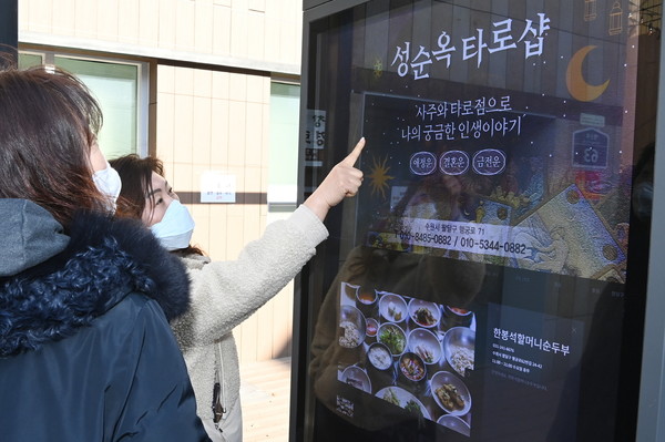 시민들이 수원시 팔달구 남문로데오거리에 설치된 디지털 옥외광고물에 송출되는 지역 업체 광고를 살펴보고 있다